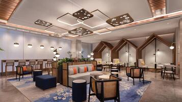 A modern hotel lobby with a seating area, a reception desk, and a staircase.
