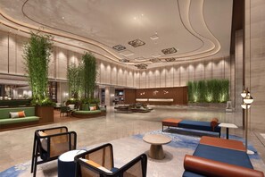 Un'ampia hall con zone salotto, una reception e piante ornamentali.