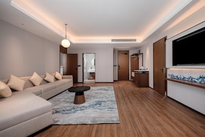 A modern living room with a sofa, a coffee table, a TV, and a wooden floor.