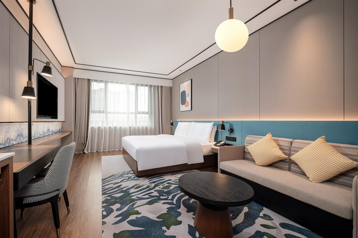 Una habitación de hotel moderna con cama, sofá, escritorio y televisor.