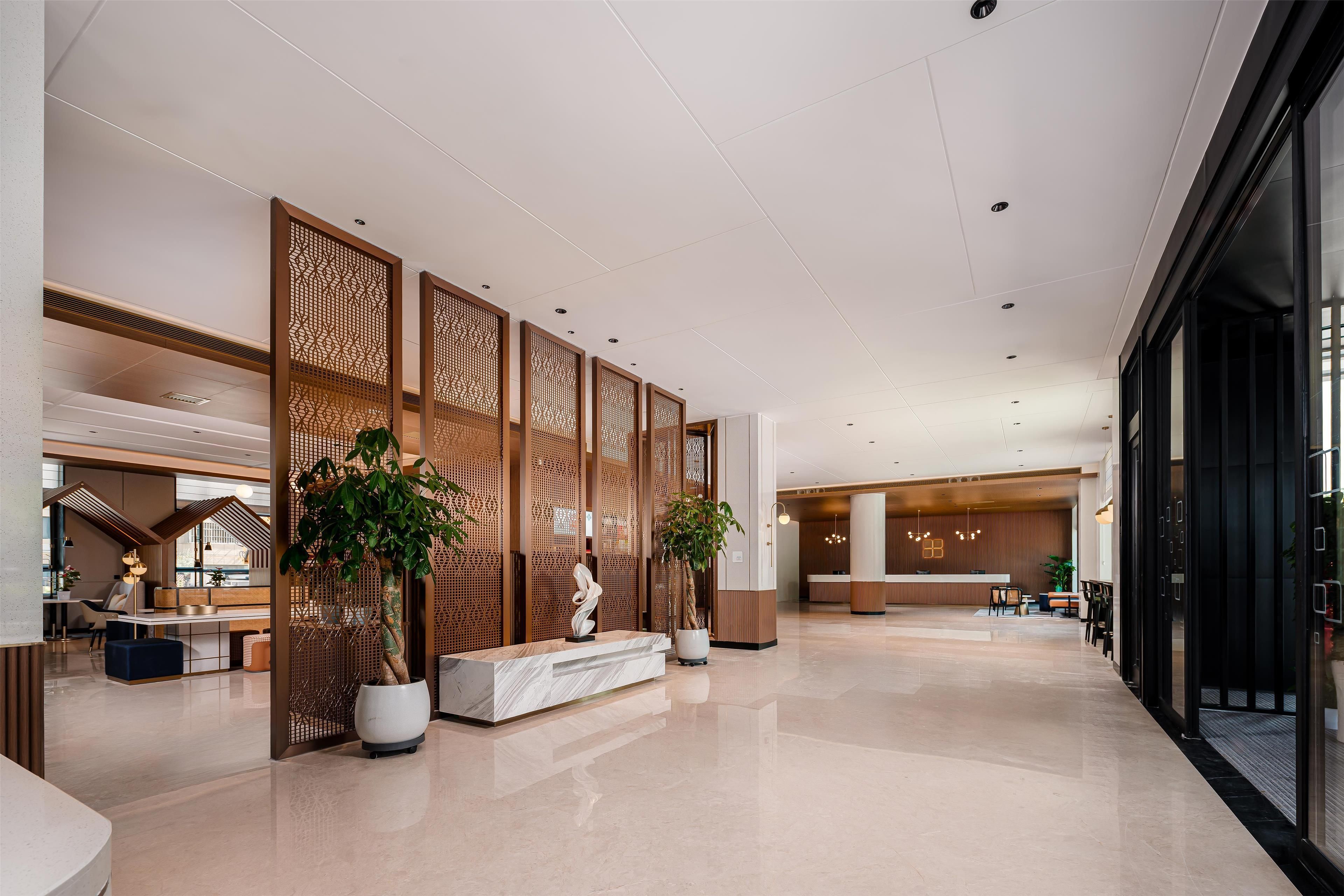 Eine geräumige Lobby mit einer Rezeption, einer Sitzecke und dekorativen Holzpaneelen.