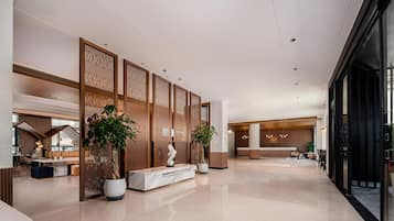A spacious lobby with a reception desk, seating area, and decorative wooden panels.