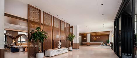 A spacious lobby with a reception desk, seating area, and decorative wooden panels.