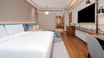 Habitación de hotel con cama, escritorio, televisión y baño a la vista.