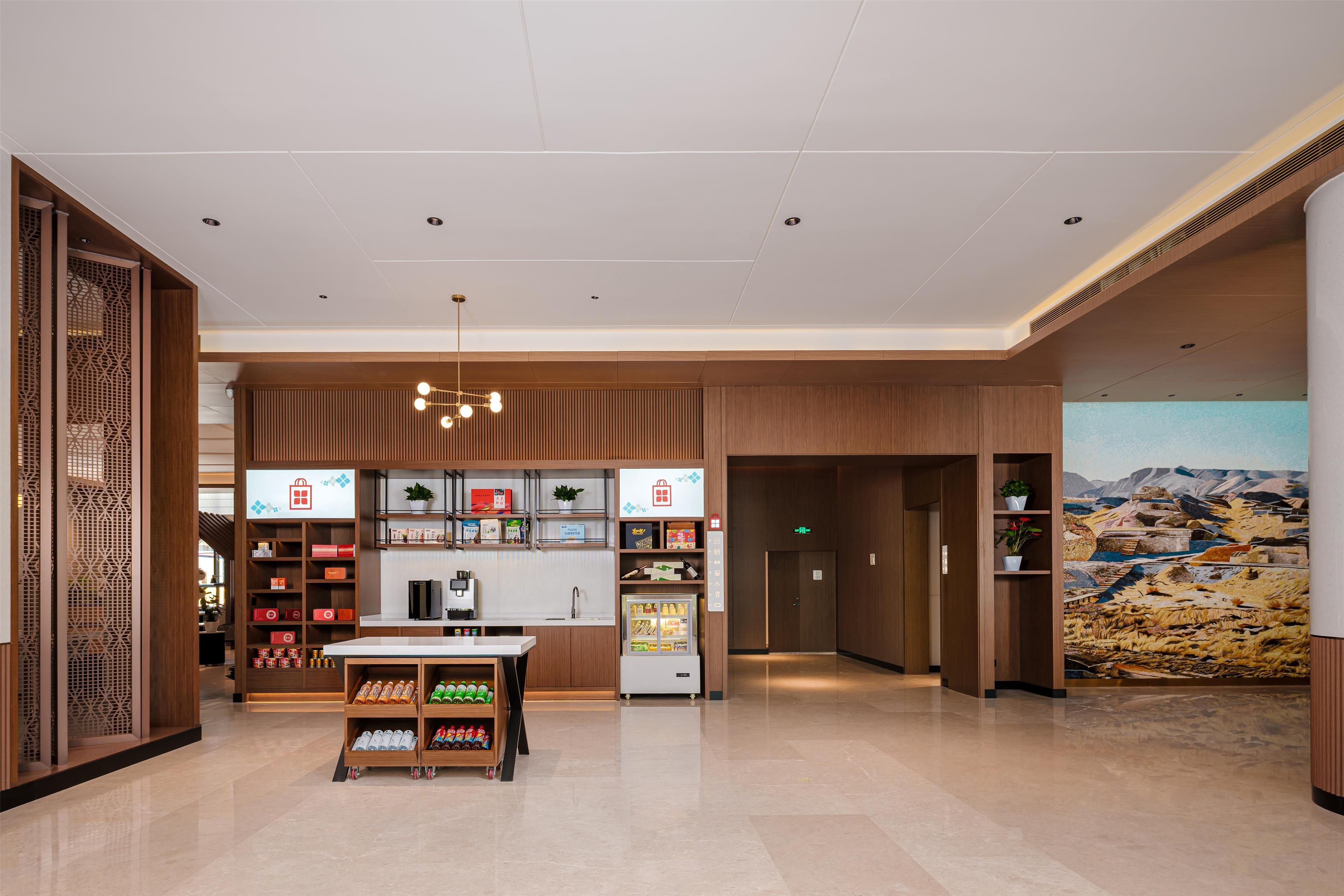 A hotel lobby with a reception desk, vending machines, and a large mural on the wall.