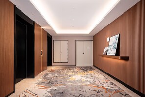 A hallway with wooden paneling, a patterned carpet, and a ceiling light fixture. - Hilton Garden Inn Yanqi Downtown (Hejing)