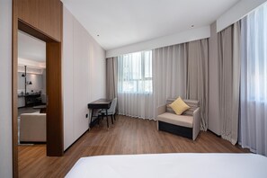 A hotel room with a bed, a desk, a chair, a sofa, and a large window with curtains. - Hilton Garden Inn Yanqi Downtown (Hejing)
