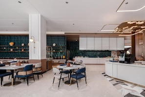 A modern restaurant interior with a central dining area, a bar, and a kitchen. - Hilton Garden Inn Yanqi Downtown (Hejing)