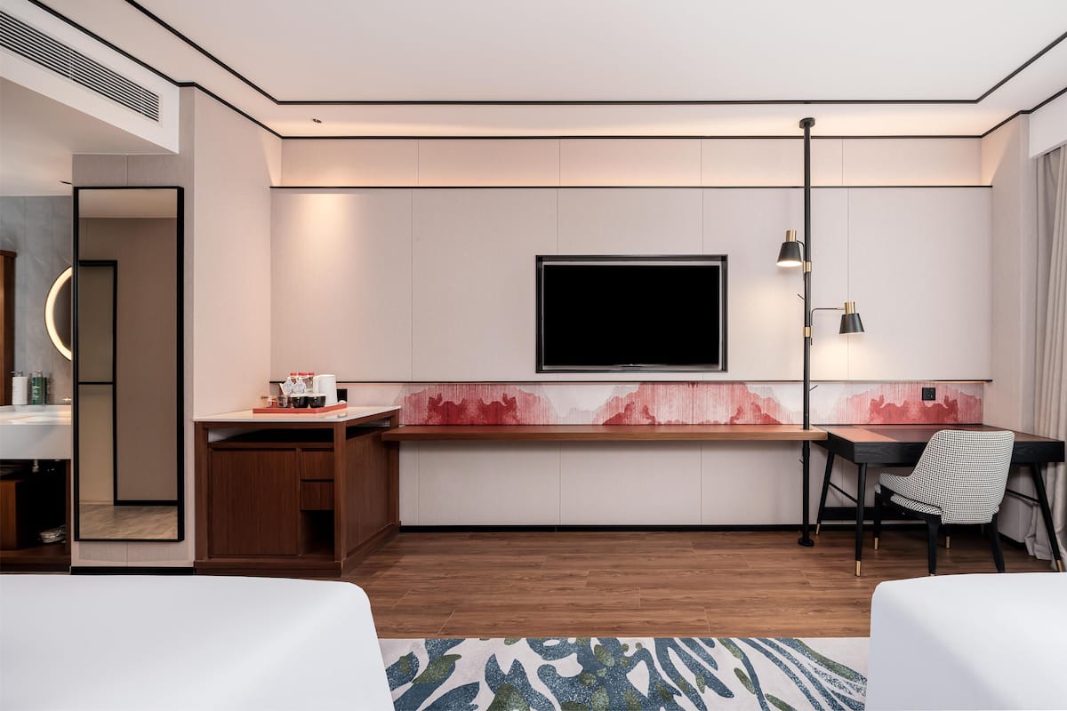 A modern hotel room with a flat-screen TV, a desk, a chair, and a bed.