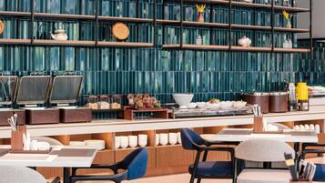 Un restaurante moderno con una barra larga, varias zonas de estar y una pared decorativa con estantes.