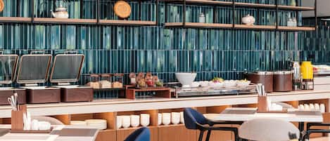 A modern restaurant with a long counter, multiple seating areas, and a decorative wall with shelves.