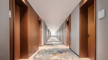 Een hotelgangen met houten deuren, een vloerbedekking en een bordje met een kamer aanduiding.