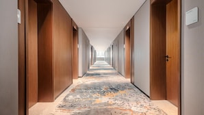 Pasillo de hotel con puertas de madera, suelo alfombrado y un cartel que indica una habitación.