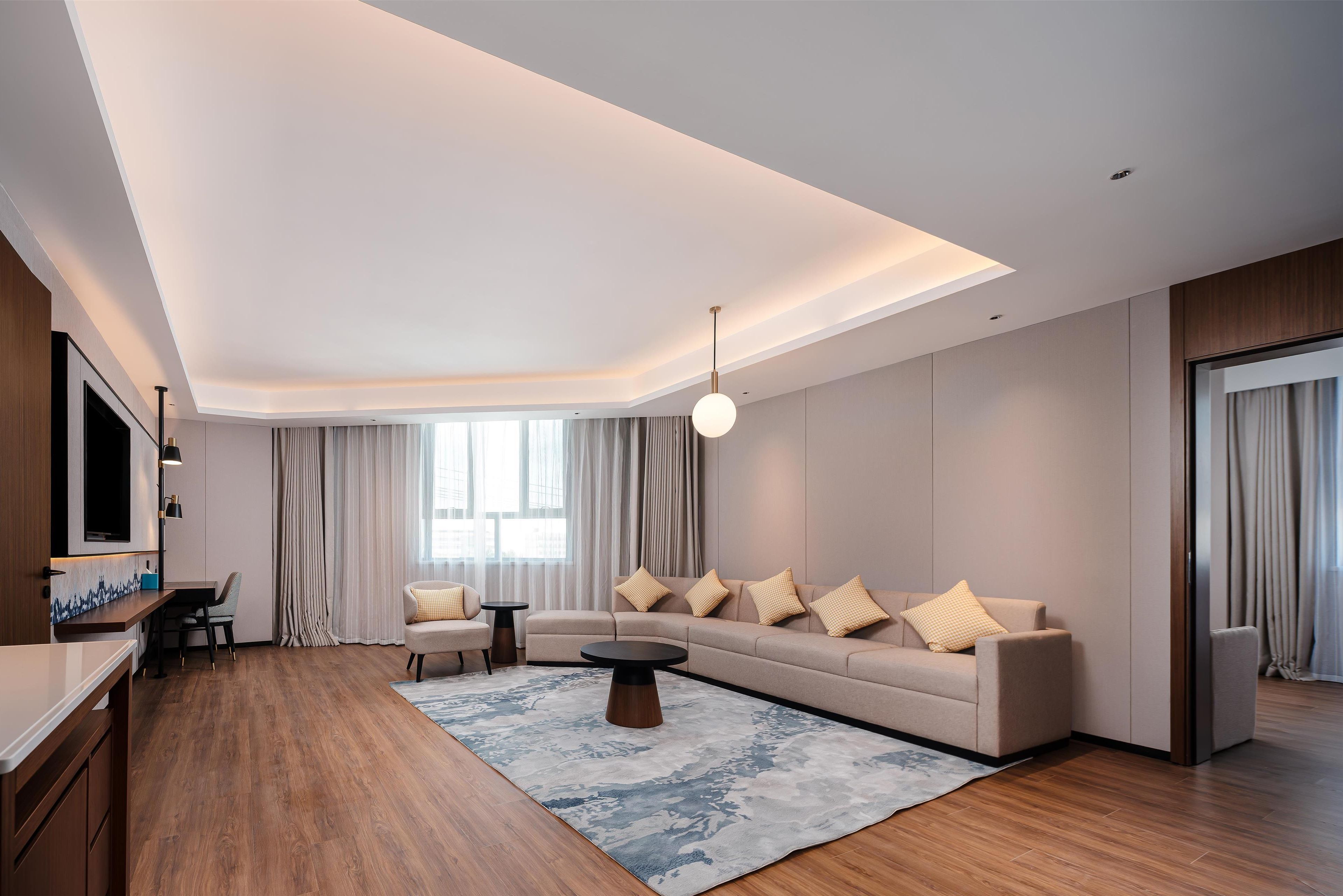 A modern living room with a sofa, coffee table, and a TV mounted on the wall.