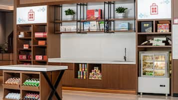 A modern retail display with shelves stocked with products, a refrigerated display case, and a table with bottled beverages.