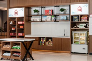 A modern retail display with shelves stocked with products, a refrigerated display case, and a table with bottled beverages. - Hilton Garden Inn Yanqi Downtown (Hejing)
