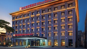 Un hotel de varios pisos con un cartel llamativo de Hilton Garden Inn.