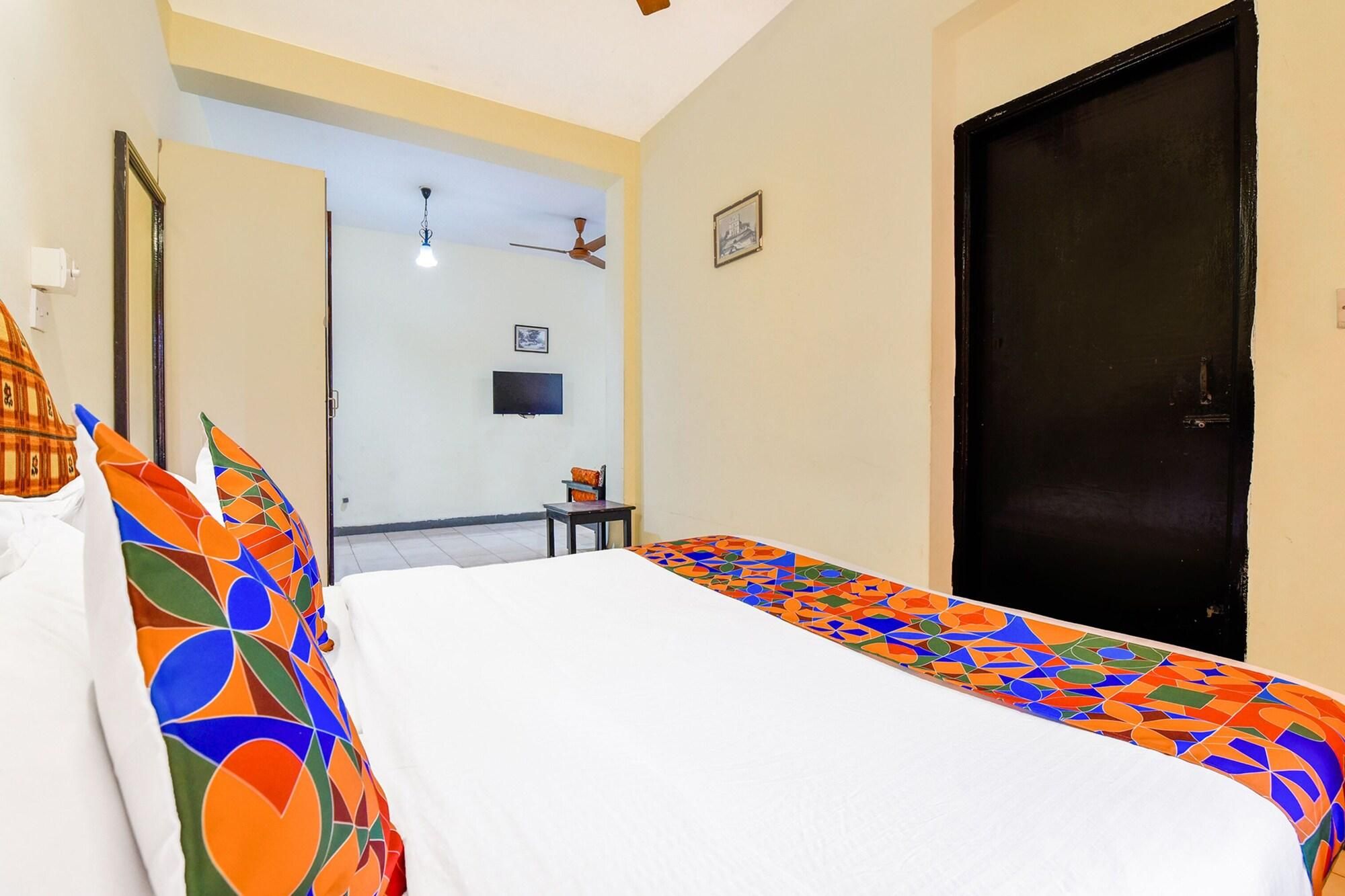 A hotel room with a bed, a desk, a chair, a television, and a door.