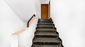 A narrow staircase with black steps leading to a wooden door at the top. - Fabexpress Alor Holiday Resort (Calangute)