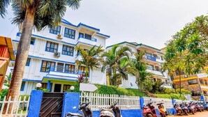 A multi-story hotel with a white facade and blue trim, featuring balconies and air conditioning units. - Fabexpress Alor Holiday Resort (Calangute)