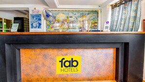 A reception area with a tiled mural depicting a coastal scene, a check-out counter, and a sign for 'fab hotels'. - Fabexpress Alor Holiday Resort (Calangute)