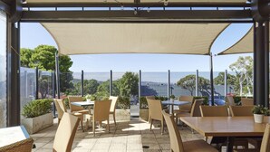 An outdoor patio with wicker furniture and a view of the sea. - Blue Gums Hotel (Adelaide)