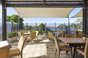 Un patio al aire libre con muebles de mimbre y vistas al mar.