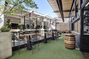 An outdoor seating area with tables and chairs, a wooden barrel, and a stone wall. - Blue Gums Hotel (Adelaide)