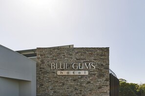 A hotel sign with the name "BLUE GUMS" and the word "hotel" below it, set against a stone wall. - Blue Gums Hotel (Adelaide)