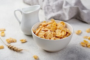Eine Schüssel Cornflakes mit einer weißen Kanne im Hintergrund.