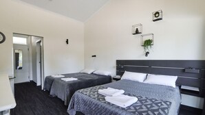 A hotel room with two beds, a mirror, a clock, and a plant on the wall. - Blue Gums Hotel (Adelaide)