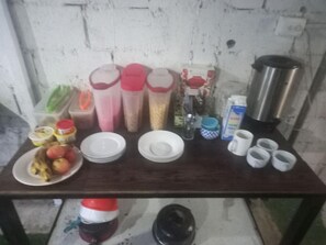 A kitchen counter with various items including plates, cups, condiments, and a coffee maker. - Hotel Cortez (San José)