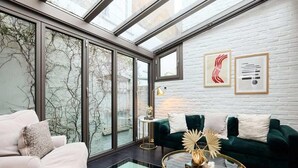 A modern living room with a glass coffee table, a green sofa, and a white armchair. - The Notting Hill Gate Crib Relaxing 2bdr House (London)