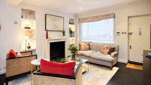A modern living room with a fireplace, a sofa, a coffee table, and a bookshelf. - The Notting Hill Gate Crib Relaxing 2bdr House (London)