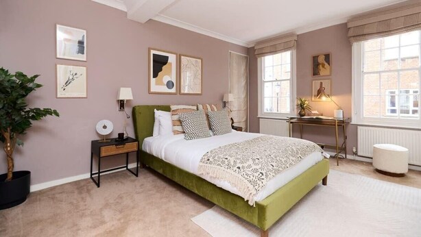 A bedroom with a green bed, a nightstand, a lamp, a potted plant, and artwork on the walls. - The Notting Hill Gate Crib Relaxing 2bdr House (London)