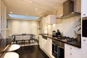 Una cocina moderna con estufa a gas, armarios blancos y tragaluz.