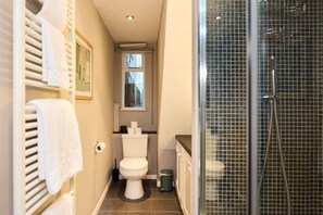 Un baño pequeño con inodoro, zona de ducha y perchero.