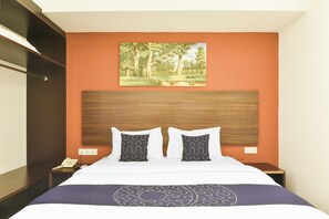 Ein Hotelzimmer mit einem Bett, zwei Nachttischen, einem Waldgemälde und einem Holzkopfstück.