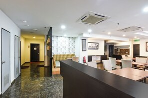 Eine Hotelhalle mit Rezeption, Sitzgelegenheiten und einer Treppe zu einer weiteren Etage.