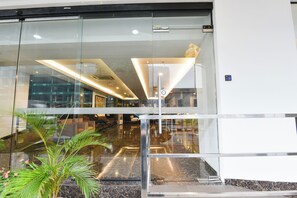 Eine moderne Lobby mit Glastüren, einem Marmorboden und einer zentralen Leuchte.