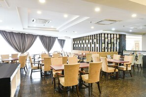 Un comedor moderno con varias mesas y sillas, una barra y una pared decorativa con elementos verticales.