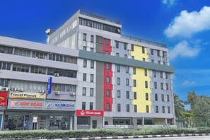 Un edificio de varios pisos con diversos comercios en la planta baja, como una agencia de viajes, una tienda de ropa y un restaurante.