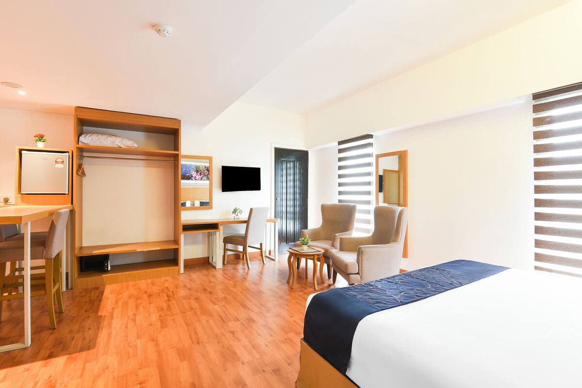Een hotelkamer met een bed, bureau, stoelen en een televisie.