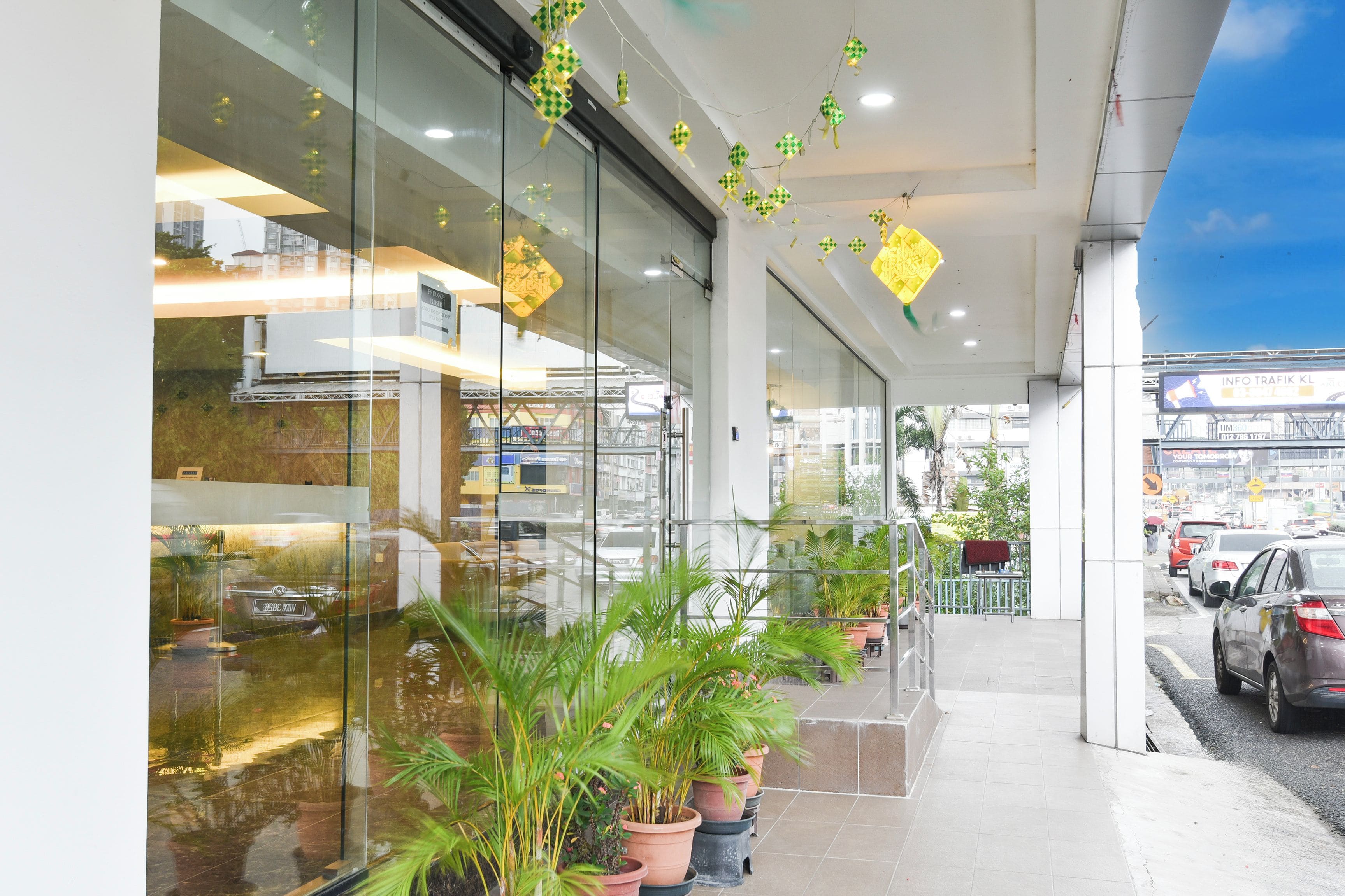 A modern building with large glass windows, potted plants, and a clear view of the street outside.