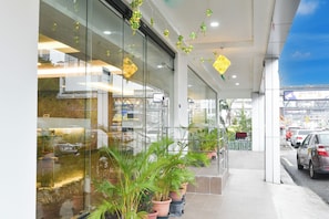 Un edificio moderno con amplios ventanales, plantas en macetas y una vista despejada de la calle.