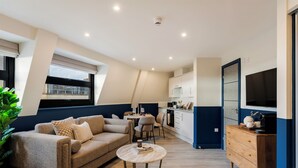 A modern living room with a sofa, coffee table, and dining area. - Clifton Village - Your Apartment (Bristol)