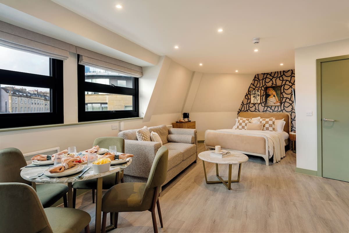 Habitación de hotel moderna con comedor, cama y vistas a la ciudad.