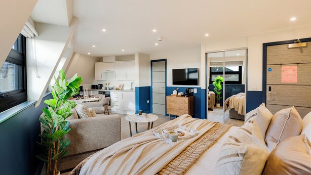 A modern hotel room with a large bed, a small sitting area, a kitchenette, and a bathroom. - Clifton Village - Your Apartment (Bristol)