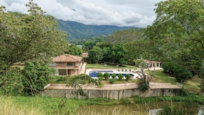 A villa with a swimming pool, surrounded by lush greenery and mountains in the background. - Tres Lagos Hotel (San Jerónimo)