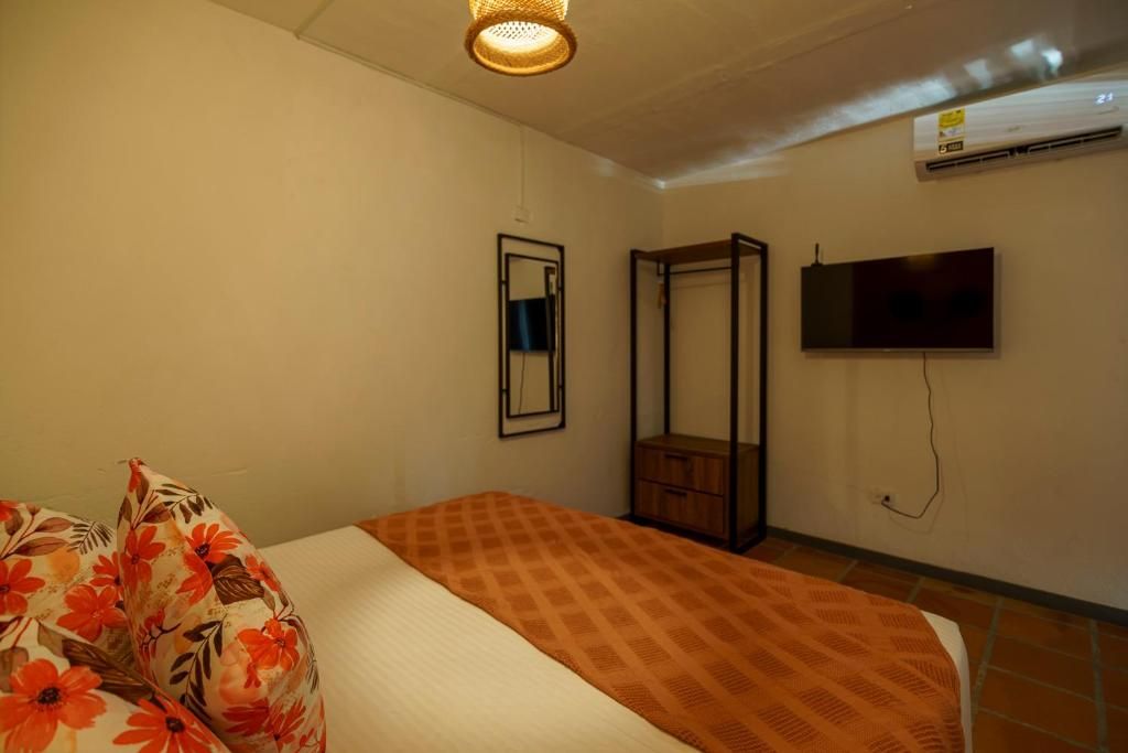 Un dormitorio con cama, espejo, armario y televisor en la pared.